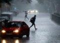 Άνθρωποι προσπαθούν να προστατευθούν από τη βροχή, στη Βαρκελόνη (φωτ.: EPA / Alberto Estevez)