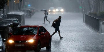 Άνθρωποι προσπαθούν να προστατευθούν από τη βροχή, στη Βαρκελόνη (φωτ.: EPA / Alberto Estevez)