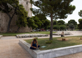 Γυναίκα κάθεται κάτω από τη σκιά ενός δέντρου ώστε να προστατευτεί από τις υψηλές θερμοκρασίες και τον καυτό ήλιο, Θεσσαλονίκη (φωτ.: ΑΠΕ-ΜΠΕ / Αχιλλέας Χήρας)