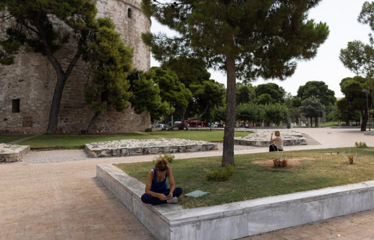 Γυναίκα κάθεται κάτω από τη σκιά ενός δέντρου ώστε να προστατευτεί από τις υψηλές θερμοκρασίες και τον καυτό ήλιο, Θεσσαλονίκη (φωτ.: ΑΠΕ-ΜΠΕ / Αχιλλέας Χήρας)