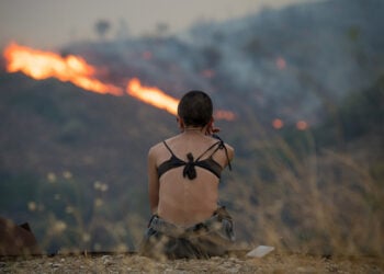 Γυναίκα κοιτάζει τις φλόγες από την πυρκαγιά στην περιοχή Ποταμιά-Πισπιλούντα στη βόρεια Χίο. Τρίτη 12 Αυγούστου 2025 (φωτ.: ΑΠΕ-ΜΠΕ / Κώστας Κουργιάς)