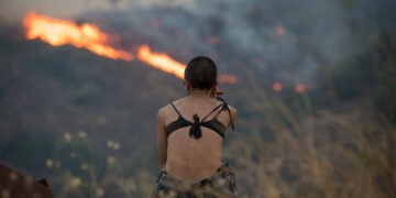 Γυναίκα κοιτάζει τις φλόγες από την πυρκαγιά στην περιοχή Ποταμιά-Πισπιλούντα στη βόρεια Χίο. Τρίτη 12 Αυγούστου 2025 (φωτ.: ΑΠΕ-ΜΠΕ / Κώστας Κουργιάς)