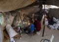 Παλαιστίνιος πατέρας με τον γιο του προσπαθεί να μαγειρέψει μέσα σε αυτοσχέδια σκηνή στον καταυλισμό της Χαν Γιουνίς, στη νότια Γάζα (φωτ.: EPA/Haitham Imad)