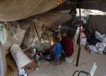 Παλαιστίνιος πατέρας με τον γιο του προσπαθεί να μαγειρέψει μέσα σε αυτοσχέδια σκηνή στον καταυλισμό της Χαν Γιουνίς, στη νότια Γάζα (φωτ.: EPA/Haitham Imad)