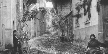 Ο δρόμος προς το Ναό της Παναγίας το 1919, μετά την επιστροφή στο Μοσχονήσι των κατοίκων του που το είχαν εγκαταλείψει στον λεγόμενο πρώτο διωγμό, του 1914. Φανερές οι ζημιές στα σπίτια (φωτ.: Αρχείο Α. Μαΐλη)