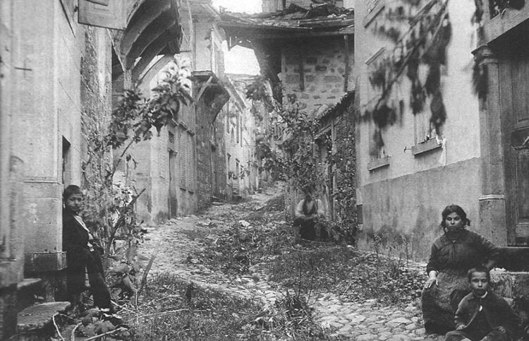 Ο δρόμος προς το Ναό της Παναγίας το 1919, μετά την επιστροφή στο Μοσχονήσι των κατοίκων του που το είχαν εγκαταλείψει στον λεγόμενο πρώτο διωγμό, του 1914. Φανερές οι ζημιές στα σπίτια (φωτ.: Αρχείο Α. Μαΐλη)