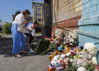 Ουκρανοί αφήνουν λουλούδια και λούτρινα παιχνίδια έξω από το κτήριο κατοικιών όπου σημειώθηκε η ρωσική επίθεση και σκοτώθηκαν δεκάδες άνθρωποι (φωτ.: EPA/Sergey Dolzhenko)