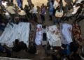 Παλαιστίνιοι στέκονται μπροστά σε σορούς μετά τους χθεσινοβραδινούς βομβαρδισμούς του Ισραήλ στη Γάζα (φωτ.: EPA/Haitham Imad)