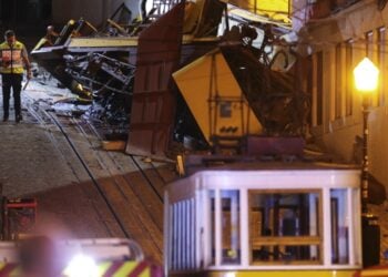 Αστυνομικός στέκεται στη σκηνή του δυστυχήματος με το κατεστραμμένο βαγόνι όπου βρήκαν το θάνατο 15 άνθρωποι (φωτ.: EPA/Miguel A. Lopes)