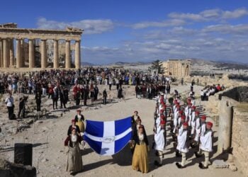 Μέλη της χορευτικής ομάδας του Λυκείου Ελληνίδων με εθνικές ενδυμασίες, κρατώντας τη Σημαία της Απελευθέρωσης και πλαισιωμένα από μαθητές και μαθήτριες της Ιονίου Σχολής, προσήλθαν στο σημείο του ιστού (φωτ.: EUROKINISSI/Γιώργος Κονταρίνης)