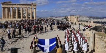 Μέλη της χορευτικής ομάδας του Λυκείου Ελληνίδων με εθνικές ενδυμασίες, κρατώντας τη Σημαία της Απελευθέρωσης και πλαισιωμένα από μαθητές και μαθήτριες της Ιονίου Σχολής, προσήλθαν στο σημείο του ιστού (φωτ.: EUROKINISSI/Γιώργος Κονταρίνης)
