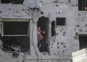 Κάτοικοι κοιτάζουν μέσα από ένα κατεστραμμένο κτήριο, μετά τους ισραηλινούς βομβαρδισμούς σε κατοικημένες περιοχές ανατολικά της Πόλης της Γάζας (φωτ.: EPA / Mohammed Saber)