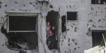 Κάτοικοι κοιτάζουν μέσα από ένα κατεστραμμένο κτήριο, μετά τους ισραηλινούς βομβαρδισμούς σε κατοικημένες περιοχές ανατολικά της Πόλης της Γάζας (φωτ.: EPA / Mohammed Saber)