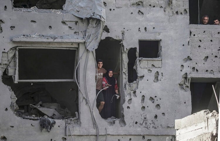 Κάτοικοι κοιτάζουν μέσα από ένα κατεστραμμένο κτήριο, μετά τους ισραηλινούς βομβαρδισμούς σε κατοικημένες περιοχές ανατολικά της Πόλης της Γάζας (φωτ.: EPA / Mohammed Saber)