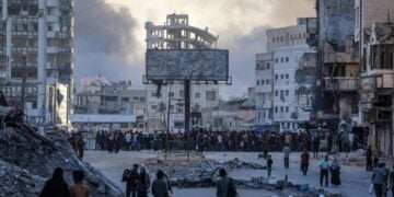 Παλαιστίνιοι κινούνται στην πλατεία Αλ Σαράγια στη Γάζα, ενώ στο βάθος υψώνεται καπνός από ισραηλινά πλήγματα στην περιοχή, παρά την έναρξη των ειρηνευτικών διαπραγματεύσεων στην Αίγυπτο μεταξύ Χαμάς και Ισραήλ (φωτ.: EPA/Mohammed Saber)