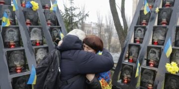 Ουκρανές αγκαλιάζονται μπροστά από μνημείο πεσόντων κοντά στην πλατεία Ανεξαρτησίας του Κιέβου (φωτ.: EPA/Sergey Dolzhenko)