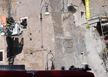 Στην αριστερή πλευρά του Πύργου των Κόμηδων πυροσβέστες προσπαθούν να απεγκλωβίσουν εργάτη, ενώ δεξιά διακρίνονται κομμάτια του τοίχου τα οποία καταρρέουν (φωτ.: EPA/Maurizio Brambatti)