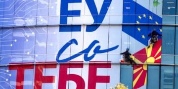 Εργάτες κολλούν τη νέα πρόσοψη των γραφείων της ΕΕ στα Σκόπια, η οποία αναγράφει «Η Ευρωπαϊκή Ένωση μαζί σου» (φωτ. αρχείου: EPA/Georgi Licovski)