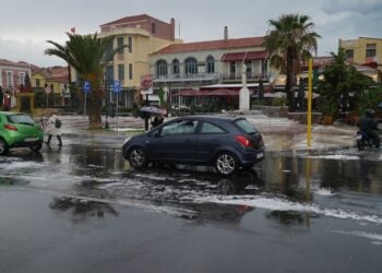 Κόσμος περπατά κρατώντας ομπρέλες, κατά τη διάρκεια της κακοκαιρίας με ισχυρή χαλαζόπτωση και βροχοπτώσεις στη Μυτιλήνη (φωτ.: ΑΠΕ-ΜΠΕ/ΗΛΙΑΣ ΜΑΡΚΟΥ)