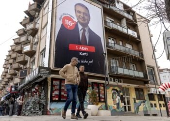 Κοσοβάροι προσπερνούν προεκλογική γιγαντοαφίσα του Άλμπιν Κούρτι στην Πρίστινα (φωτ.: EPA/Georgi Licovski)