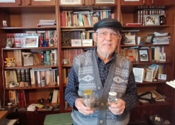 Ο Πέτρος Σιδηρόπουλος στο γραφείο του, κρατώντας γη και ύδωρ από την Πατρίδα, το Κιουλαπέρτ του Καρς (φωτ.: Αλεξία Ιωαννίδου)