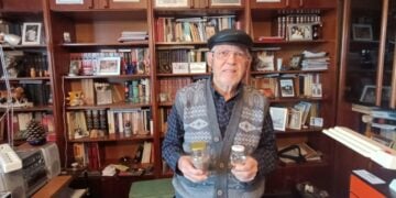 Ο Πέτρος Σιδηρόπουλος στο γραφείο του, κρατώντας γη και ύδωρ από την Πατρίδα, το Κιουλαπέρτ του Καρς (φωτ.: Αλεξία Ιωαννίδου)