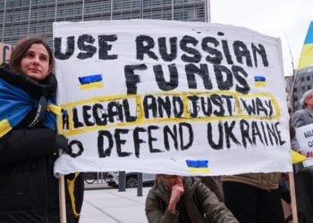 Ουκρανοί κρατούν πανό που αναγράφει «Χρησιμοποιείστε ρωσικά κεφάλαια: Ένας νόμιμος και σωστός τρόποος να υπερασπιστείτε την Ουκρανία» έξω από το κτήριο όπου συνεδριάζει το Ευρωπαϊκό Συμβούλιο των υπουργών Οικονομικών στις Βρυξέλλες (φωτ.: EPA/Olivier Hoslet)