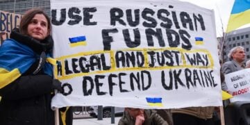 Ουκρανοί κρατούν πανό που αναγράφει «Χρησιμοποιείστε ρωσικά κεφάλαια: Ένας νόμιμος και σωστός τρόποος να υπερασπιστείτε την Ουκρανία» έξω από το κτήριο όπου συνεδριάζει το Ευρωπαϊκό Συμβούλιο των υπουργών Οικονομικών στις Βρυξέλλες (φωτ.: EPA/Olivier Hoslet)