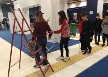 Παιδιά που μετέχουν στη δράση είτε κρατούν το λευκό μπαστούνι, είτε συνοδεύουν συμμαθητές τους ανάμεσα σε τεχνητά εμπόδια, προκειμένου να βιώσουν την καθημερινότητα των ατόμων με προβλήματα όρασης (φωτ.: Έλλη Τσολάκη)