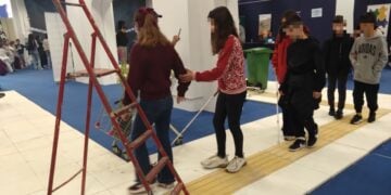 Παιδιά που μετέχουν στη δράση είτε κρατούν το λευκό μπαστούνι, είτε συνοδεύουν συμμαθητές τους ανάμεσα σε τεχνητά εμπόδια, προκειμένου να βιώσουν την καθημερινότητα των ατόμων με προβλήματα όρασης (φωτ.: Έλλη Τσολάκη)