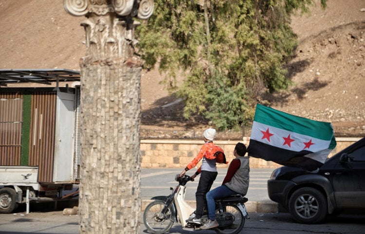Παιδιά στη Χάμα κρατούν τη νέα σημαία της Συρίας, κατά τη διάρκεια των εορτασμών για τον έναν χρόνο από την απελευθέρωση της πόλης, 5 Δεκεμβρίου 2025 (φωτ.: EPA / Bilal al-Hammoud)