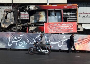 Ιρανός περπατάει μπροστά από ένα πυροσβεστικό όχημα που κάηκε κατά τη διάρκεια των αντικυβερνητικών διαδηλώσεων, στην Τεχεράνη (φωτ.: EPA/ Abedin Taherkenareh)