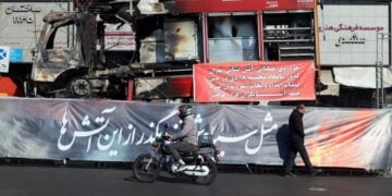 Ιρανός περπατάει μπροστά από ένα πυροσβεστικό όχημα που κάηκε κατά τη διάρκεια των αντικυβερνητικών διαδηλώσεων, στην Τεχεράνη (φωτ.: EPA/ Abedin Taherkenareh)