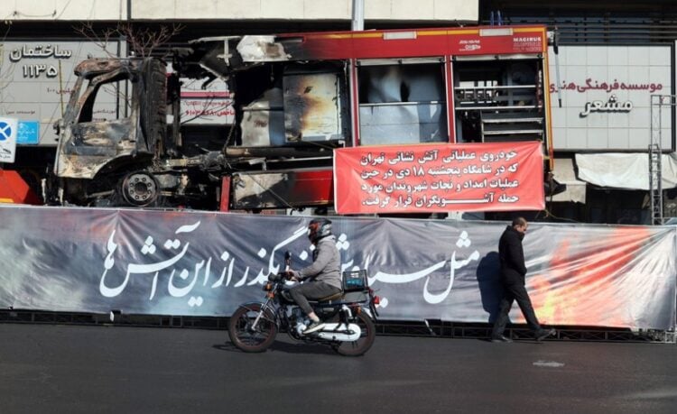 Ιρανός περπατάει μπροστά από ένα πυροσβεστικό όχημα που κάηκε κατά τη διάρκεια των αντικυβερνητικών διαδηλώσεων, στην Τεχεράνη (φωτ.: EPA/ Abedin Taherkenareh)