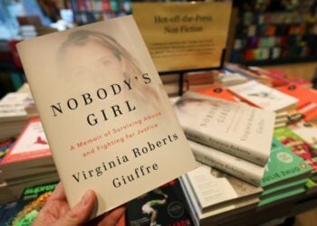 Πελάτης βιβλιοπωλείου κρατά τα απομνημονεύματα της Βιρτζίνια Τζουφρέ, η οποία αυτοκτόνησε την άνοιξη του 2025, αφού είχε κατηγορήσει για χρόνια τον πρώην πρίγκιπα Άντριου και τον Τζέφρι Έπστιν ότι την είχαν κακοποιήσει σεξουαλικά (φωτ.: EPA/Andy Rain)