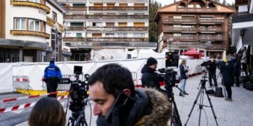 Δημοσιογράφοι στέκονται έξω από τα συντρίμμια του μοιραίου μπαρ, όπου τουλάχιστον 47 άνθρωποι βρήκαν τραγικό θάνατο και ορισμένες σοροί εξακολουθούν να βρίσκονται εκεί (φωτ.: EPA/Jean-Christophe Bott)