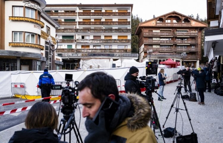 Δημοσιογράφοι στέκονται έξω από τα συντρίμμια του μοιραίου μπαρ, όπου τουλάχιστον 47 άνθρωποι βρήκαν τραγικό θάνατο και ορισμένες σοροί εξακολουθούν να βρίσκονται εκεί (φωτ.: EPA/Jean-Christophe Bott)