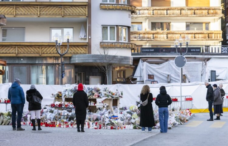 Πολίτες στέκονται μπροστά στον αυτοσχέδιο βωμό στο σημείο της τραγωδίας στο Κραν Μοντανά (φωτ.: EPA/Cyril Zingaro)