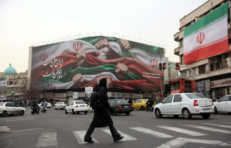 Ιρανή προσπερνά γιγαντοαφίσα που γράφει «Το Ιράν είναι η πατρίδα μας», στην Τεχεράνη (φωτ.: EPA/Abedin Taherkenareh)
