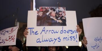 Ιρανοί φοιτητές κρατούν πανό στη διάρκεια διαμαρτυρίας μπροστά από τη βρετανική πρεσβεία στην Τεχεράνη. Στο κεντρικό πανό απεικονίζεται η απόπειρα δολοφονίας του Ντ. Τραμπ τον Ιούλιο του 2024 με τη φράση «Το βέλος δεν αστοχεί πάντα» (φωτ.: EPA/Abedin Taherkenareh)