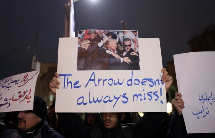 Ιρανοί φοιτητές κρατούν πανό στη διάρκεια διαμαρτυρίας μπροστά από τη βρετανική πρεσβεία στην Τεχεράνη. Στο κεντρικό πανό απεικονίζεται η απόπειρα δολοφονίας του Ντ. Τραμπ τον Ιούλιο του 2024 με τη φράση «Το βέλος δεν αστοχεί πάντα» (φωτ.: EPA/Abedin Taherkenareh)
