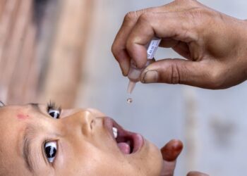 Ένας εργαζόμενος στον τομέα της υγείας χορηγεί εμβόλιο πολιομυελίτιδας σε παιδί σε χωριό του Νεπάλ, μετά από συνεργασία της κυβέρνησης της χώρας με τον Παγκόσμιο Οργανισμό Υγείας (φωτ.: EPA/Narendra Shrestha)