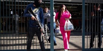 Μέλος της ένοπλης ομάδας «Colectivos» φρουρεί την είσοδο ενός σουπερμάρκετ στο Καράκας, εντείνοντας την αβεβαιότητα των πολιτών για την επόμενη ημέρα μετά τη σύλληψη του Νικολάς Μαδούρο (φωτ.: EPA/Ronald Penar)