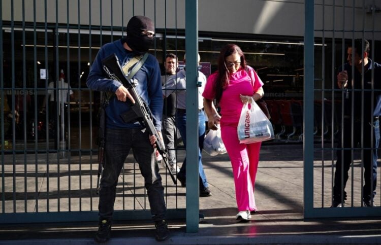 Μέλος της ένοπλης ομάδας «Colectivos» φρουρεί την είσοδο ενός σουπερμάρκετ στο Καράκας, εντείνοντας την αβεβαιότητα των πολιτών για την επόμενη ημέρα μετά τη σύλληψη του Νικολάς Μαδούρο (φωτ.: EPA/Ronald Penar)