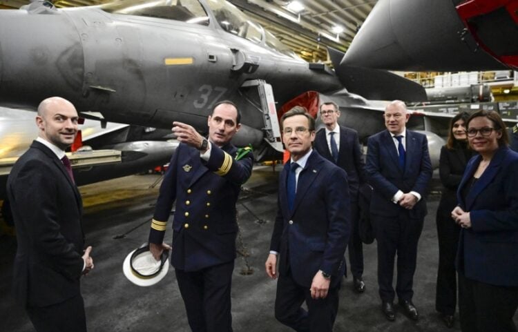 Ο κυβερνήτης του γαλλικού αεροπλανοφόρου Σαρλ Ντε Γκολ (Charles De Gaulle R91), καπετάνιος Τομά Πουγκά(δεύτερος από αριστερά), καθοδηγεί τον Σουηδό πρωθυπουργό Ουλφ Κρίστερσον (τρίτος από αριστερά), τον Γάλλο υπουργό Εξωτερικών Ζαν Νοέλ Μπαρό (αριστερά) και την Σουηδή υπουργό Εξωτερικών Μαρία Μάλμερ Στένεργκαρντ ανάμεσα στα μαχητικά αεροσκάφη. Το αεροπλανοφόρο έχει ελλιμενιστεί στο Μάλμε της Σουηδίας (φωτ.: EPA/Johan Nilsson)