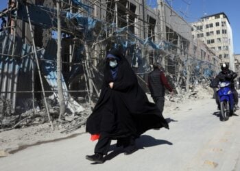 Ιρανή περπατά μπροστά από κατεστραμμένο κτήριο στο κέντρο της Τεχεράνης (φωτ.: EPA/Abedin Taherkenareh)