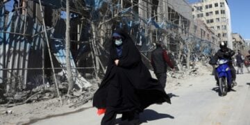 Ιρανή περπατά μπροστά από κατεστραμμένο κτήριο στο κέντρο της Τεχεράνης (φωτ.: EPA/Abedin Taherkenareh)