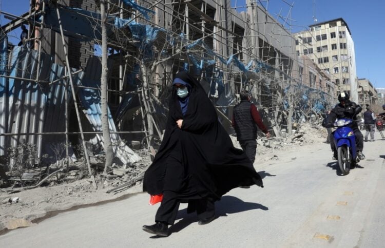 Ιρανή περπατά μπροστά από κατεστραμμένο κτήριο στο κέντρο της Τεχεράνης (φωτ.: EPA/Abedin Taherkenareh)