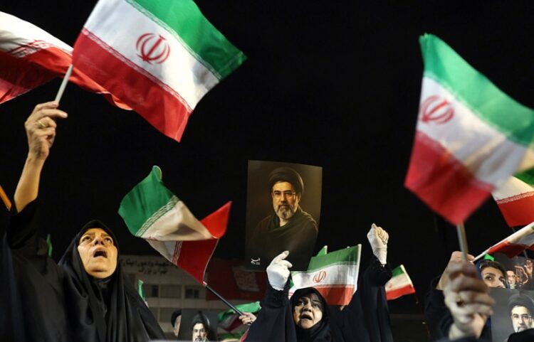 Ιρανοί με σημαίες και αφίσες του νέου ανώτατου ηγέτη της χώρας, Μοτζταμπά Χαμενεΐ μετέχουν σε συγκέντρωση στην Τεχεράνη (φωτ.: EPA/Abedin Taherkenareh)