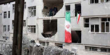 Ιρανοί στέκονται μέσα σε κατεστραμμένο κτήριο κατοικιών στη νότια Τεχεράνη (φωτ.: EPA/Abedin Taherkenareh)